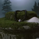 Ancient Stones by Yuano: A sacred obsidian and Dzi bead relic resting on a mossy altar of time.