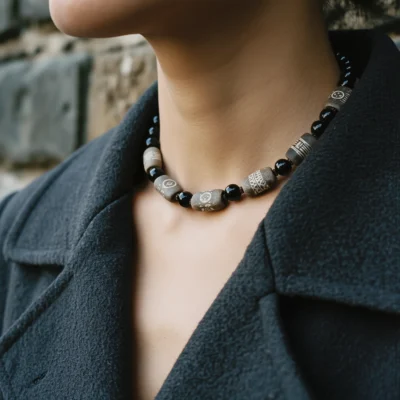 Covenant No. 01 — Lifestyle Observational Poise Covenant No. 01: The Void necklace worn by a model in a structured grey wool coat.