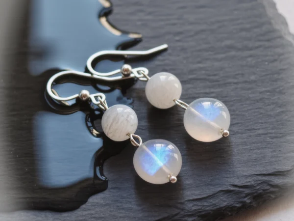 Fluidity No. 03 — Moon on Water Main Perspective Fluidity No. 03: Moon on Water hand-knotted earrings featuring Sichuan Moonstone and Anhui White Agate on a wet dark slate.