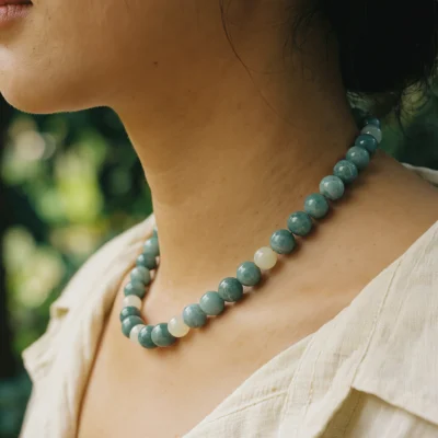 Fluidity No. 04 — Lifestyle Grounding Perspective Fluidity No. 04: Aqua Stillness necklace worn by a model, demonstrating its mineral stability and clarity against a linen garment.