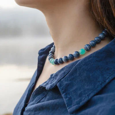Fluidity No. 06 — Lifestyle Flowing Perspective Fluidity No. 06: Mist & Dew necklace worn by a model, demonstrating the deep blue and turquoise mineral contrast against a navy garment.
