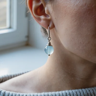 Fluidity No. 07 — Lifestyle Radiant Perspective Fluidity No. 07: Glacial Echo earrings worn by a model, demonstrating the crystalline clarity against a grey knitted sweater.
