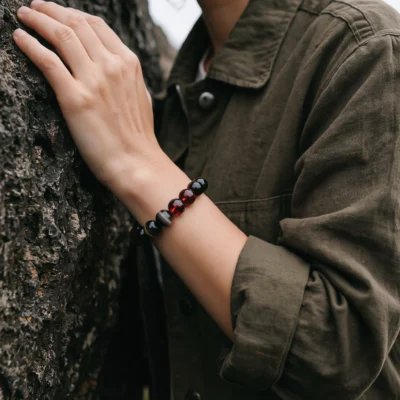 Fortress No. 02 — Lifestyle Observational Poise Fortress No. 02: Warrior's Shield bracelet worn by a model in a rugged olive green jacket against a textured rock wall.