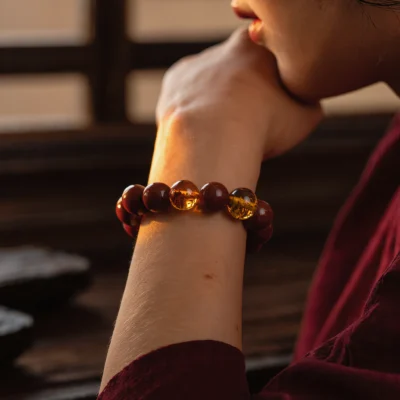 yuano-fortress-no-06-lifestyle-bracelet-worn-crimson-garment-sacred-warmth.webp Fortress No. 06: Crimson Vow bracelet worn on a wrist against a deep red garment during a quiet sunset.