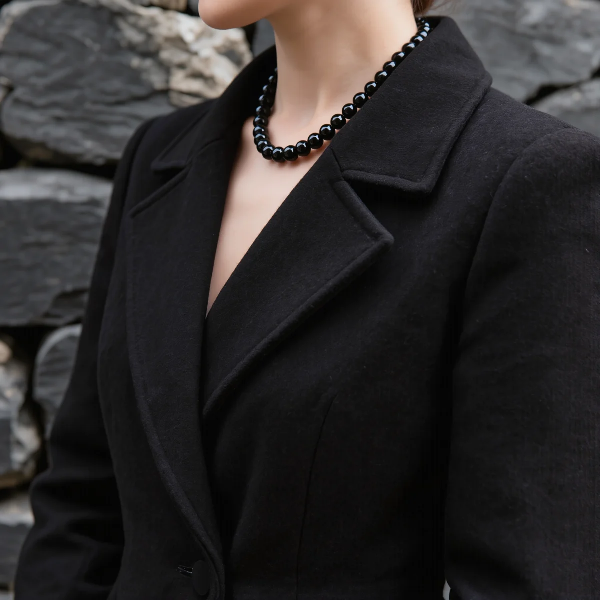 Fortress No. 09 — Lifestyle Observational Poise Fortress No. 09: Obsidian Wall necklace worn by a model in a structured black coat.