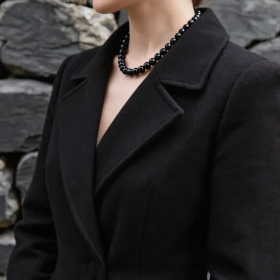 Fortress No. 09 — Lifestyle Observational Poise Fortress No. 09: Obsidian Wall necklace worn by a model in a structured black coat.