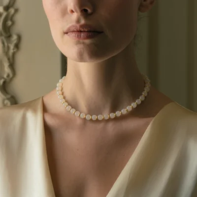 Origin No. 09 — Lifestyle Wearing Perspective Origin No. 09: Silent Root necklace worn by a model, demonstrating the elegant drape and purity against a silk champagne garment.