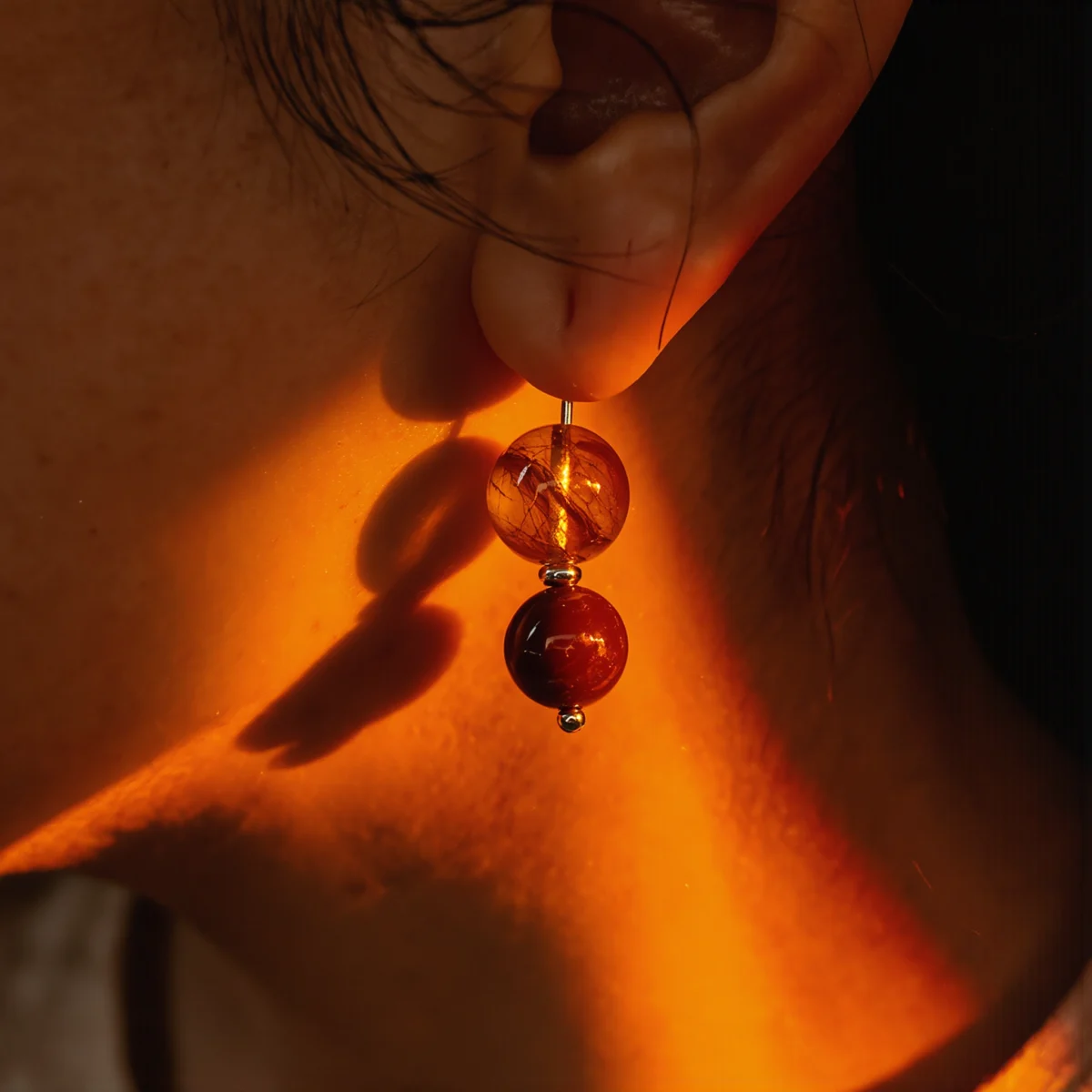 Origin No. 10 — Lifestyle Radiant Perspective Origin No. 10: Terrestrial Glow earrings worn by a model, illuminated by a dramatic warm light beam against deep shadows.