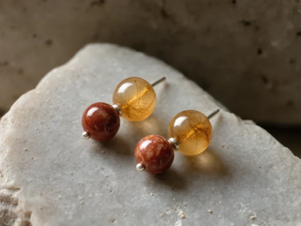 Origin No. 10 — Terrestrial Glow Main Perspective Origin No. 10: Terrestrial Glow hand-knotted earrings featuring Xinjiang Jinsiyu and Sichuan Nanhong on a natural stone altar.