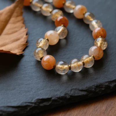 Radiance No. 01 — Solar Spark Main Perspective Radiance No. 01: Solar Spark hand-knotted necklace featuring Donghai Rutilated Quartz and Inner Mongolia Sunstone on slate.