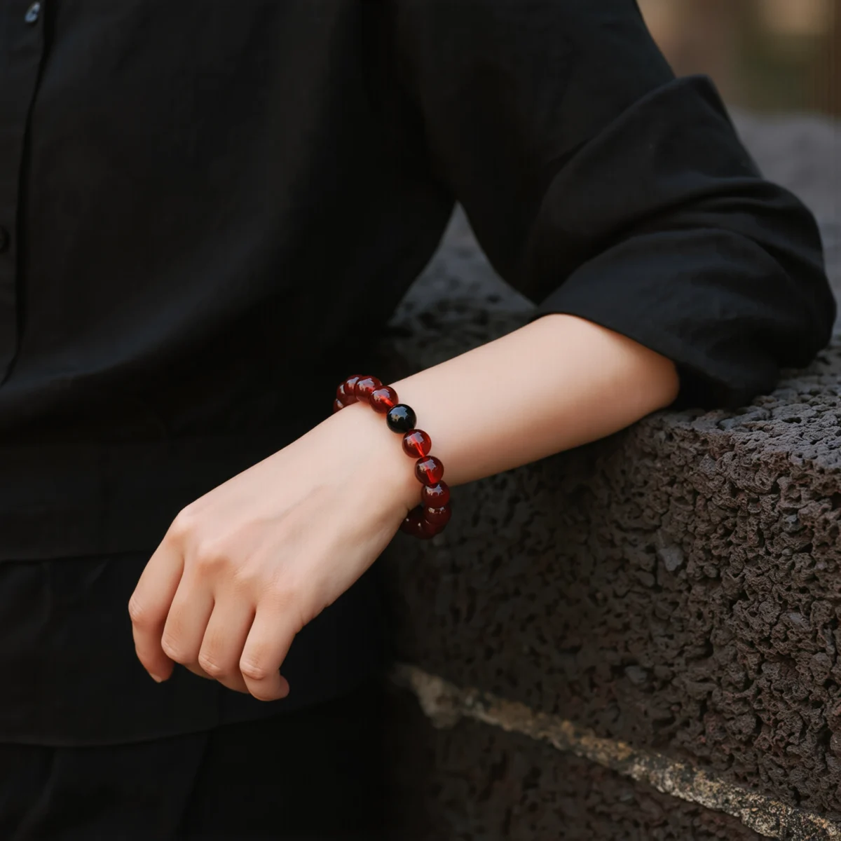 Radiance No. 08 — Lifestyle Observational Stillness Radiance No. 08: Molten Core bracelet worn on a wrist against a dark linen garment and ancient stone wall.