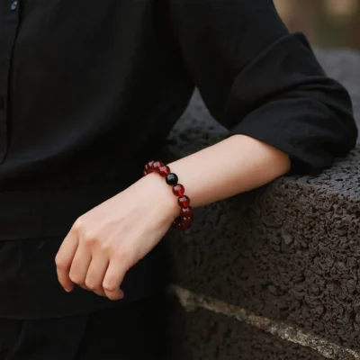 Radiance No. 08 — Lifestyle Observational Stillness Radiance No. 08: Molten Core bracelet worn on a wrist against a dark linen garment and ancient stone wall.